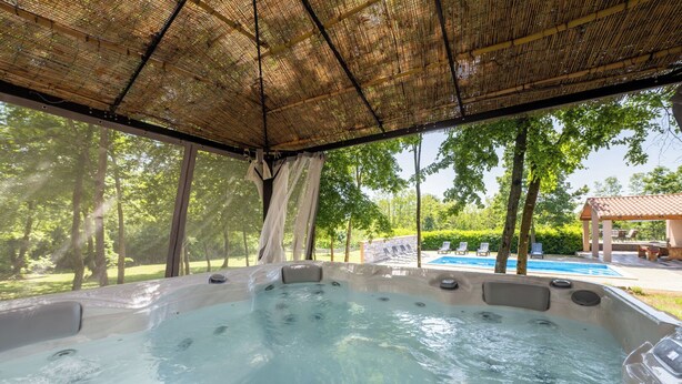 A hot tub area with a bamboo roof, surrounded by trees and a pool. - Villa Eden (Istria - Labin) (Labin)