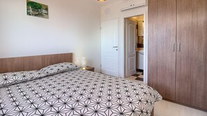 A bedroom with a geometric-patterned bedspread, a wooden wardrobe, and a painting on the wall. - Villa MAREVISTA (Istria - Brovinje) (Brovinje)