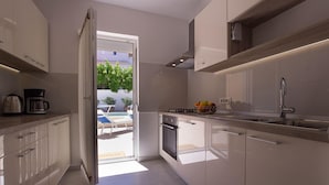 Una cocina moderna con armarios blancos, horno empotrado y un lavabo.