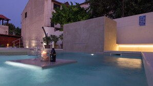 Un área de piscina al aire libre con una silla de descanso, una botella y velas.