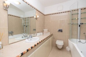 A modern bathroom with a large mirror, two sinks, a toilet, and a glass-enclosed shower. - Classy apt W terrace@teniscourt (Split)