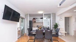 Un comedor moderno con suelo de madera, una mesa con cuatro sillas y un televisor de pantalla plana montado en la pared.