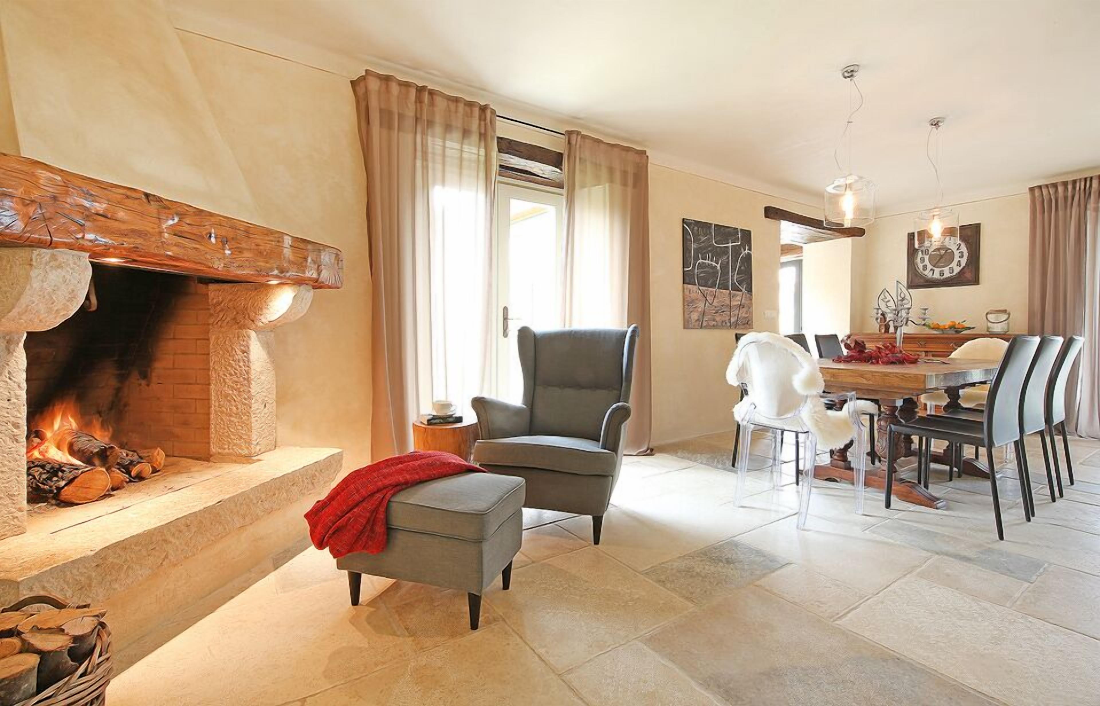 Un salon chaleureux avec une cheminée, un coin repas avec une table et des chaises, et un fauteuil confortable.
