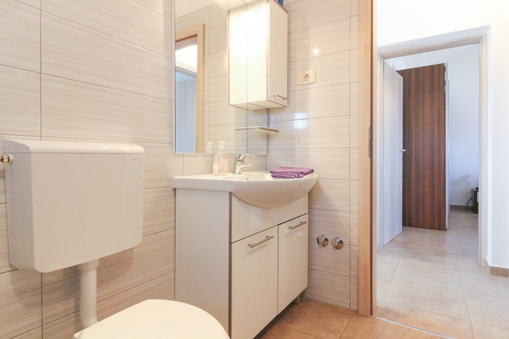 A modern bathroom with a toilet, sink, and mirror.