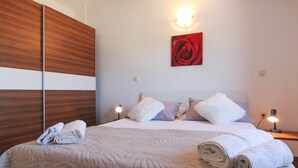 A neatly made bed with a quilt, two bedside lamps, a red rose painting, and a wooden headboard. - Villa Marina (Istria - Paradiž) (Paradiž)