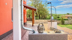 A courtyard with a red wall, a pergola, and a stone sculpture. - Villa Marina (Istria - Paradiž) (Paradiž)