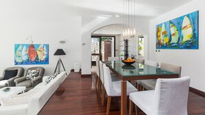 A modern dining area with a glass table and chairs, a white sofa, and two paintings on the walls. - Villa Punat seafront villa by Wiibuk (Kvarner - Punat) (Punat)