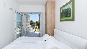 A modern bedroom with a bed, a wooden wardrobe, and a framed painting on the wall. - Villa Punat seafront villa by Wiibuk (Kvarner - Punat) (Punat)