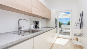 A modern kitchen with a built-in sink, a coffee maker, and a window overlooking a balcony. - Villa Vista (Kvarner - Opatija) (Opatija)