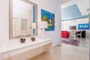 A modern bathroom with a white vanity, a large mirror, and a painting above the mirror.