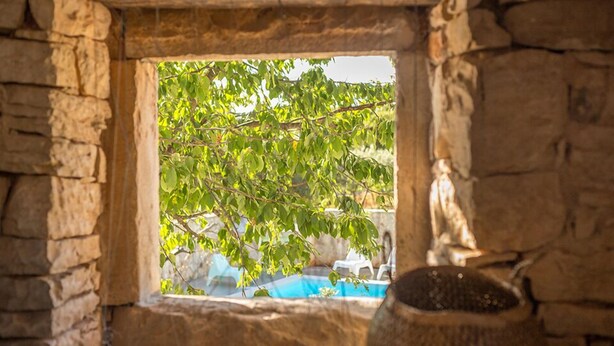 A stone-framed window with a view of a tree and a swimming pool. - Villa KALU (Istria - Mrgani) (Mrgani)