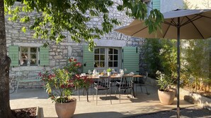 An outdoor dining area with a stone building, green shutters, and potted plants. - Villa KALU (Istria - Mrgani) (Mrgani)
