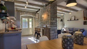 A modern kitchen with a stone accent wall, a wooden dining table, and bar stools. - Villa KALU (Istria - Mrgani) (Mrgani)