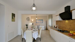 A modern kitchen with white cabinets, a wooden countertop, and a black TV mounted above. - Villa Natali (Istria - Galižana) (Galižana)