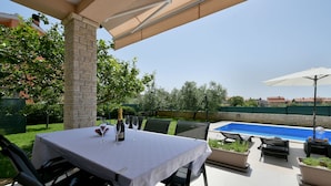 An outdoor patio with a table set for dining, a pool, and a view of the surrounding area. - Villa Natali (Istria - Galižana) (Galižana)