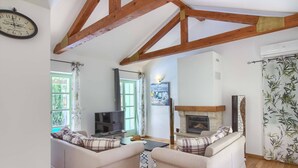 A living room with two sofas, a television, a fireplace, and a clock on the wall.