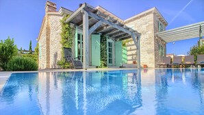 A pool area with a stone building, a pergola, and outdoor seating.