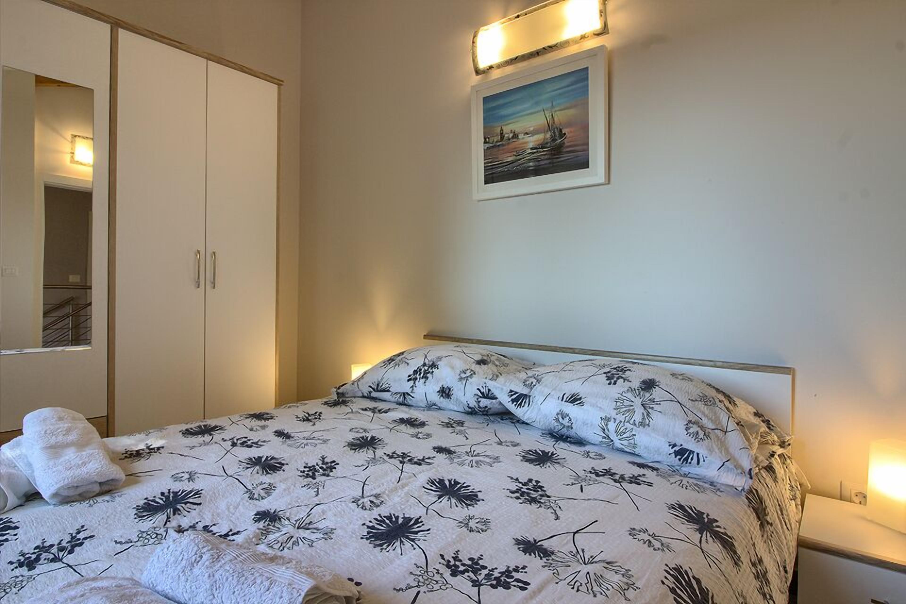 A bedroom with a bed, a wardrobe, and a painting on the wall.
