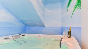A hot tub with a sky-themed ceiling, a bottle of champagne, and two glasses.