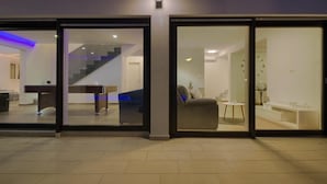 A modern interior with a pool table, a sofa, and a dining area visible through glass doors. - Villa LUKA (Istria - Loborika) (Loborika)