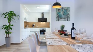 A modern dining area with a wooden table, white chairs, and a large potted plant. - Villa LUKA (Istria - Loborika) (Loborika)
