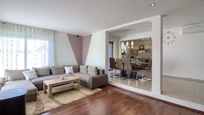 A modern living room with a sofa, coffee table, and a dining area with chairs and a table.