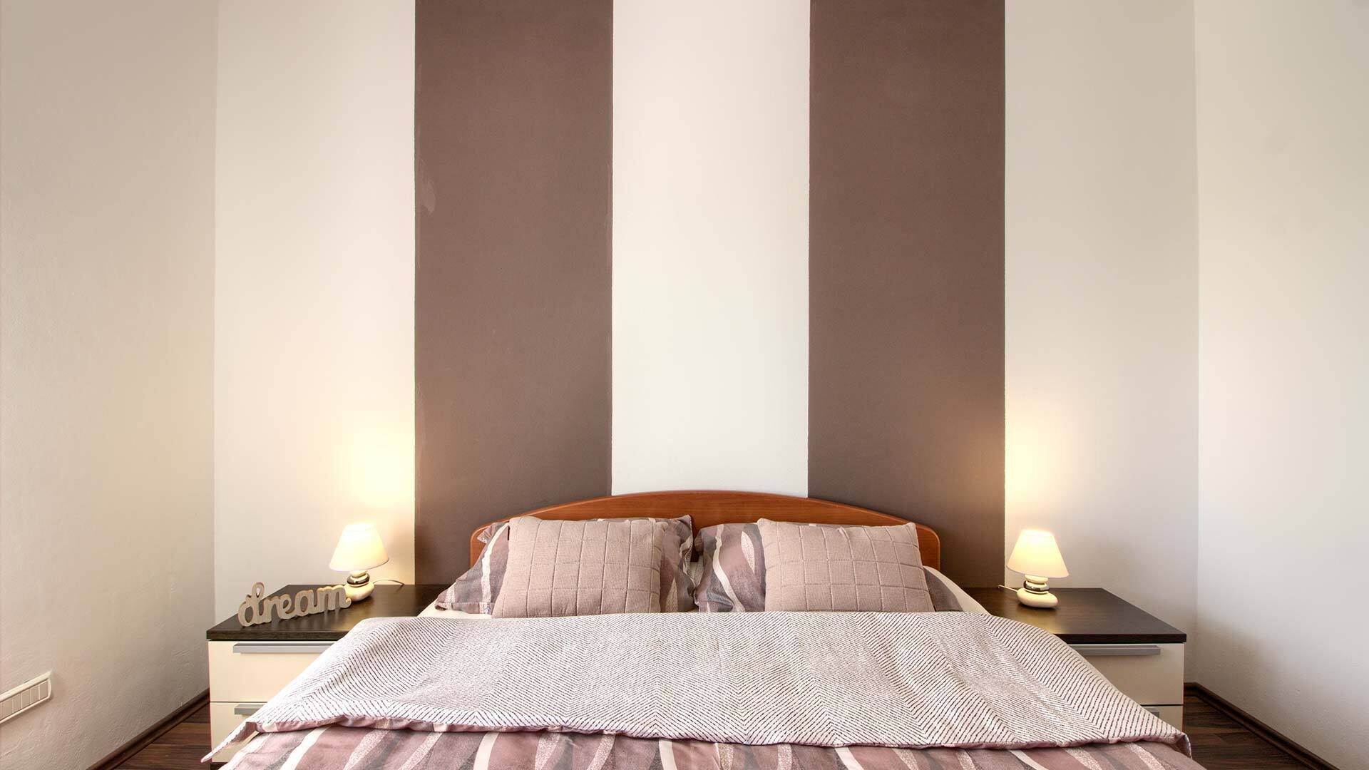 Une chambre à coucher avec un lit, deux tables de chevet et deux lampes.