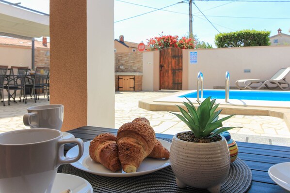 A table with croissants, a mug, and a potted plant.