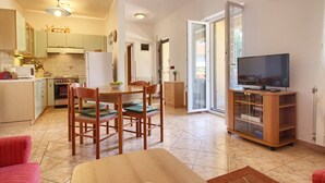 Ett kompakt bostadsutrymme med ett kök, en matplats och en tv som står på ett träställ.