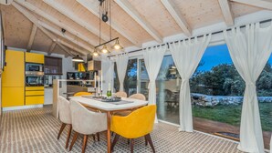 A dining area with a table and chairs, a kitchen with yellow cabinets, and a view of the outdoors. - Villa NEVIA (Istria - Ripenda Verbanci) (Ripenda Verbanci)