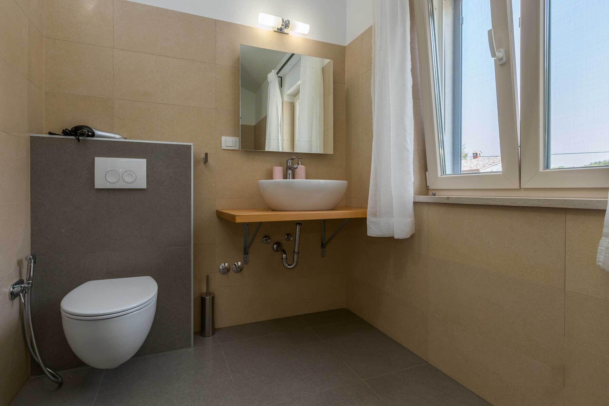 A bathroom with a toilet, a sink, a mirror, and a shower.