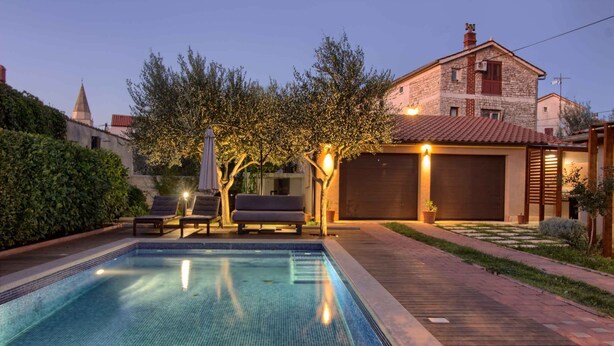A swimming pool with lounge chairs, a wooden deck, and a stone building in the background. - Villa Donatella (Istria - Sisan) (Sisan)