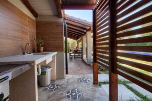 Enjoy al fresco dining under a shaded pergola with a sink and adjacent patio seating.