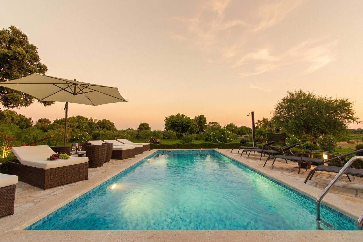 A swimming pool with lounge chairs and an umbrella.