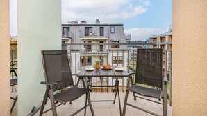 A balcony with a table and chairs, a small plant, and a plate of bread. - Charming Studio with Balcony | Parking | Close to the Beach (Świnoujście)
