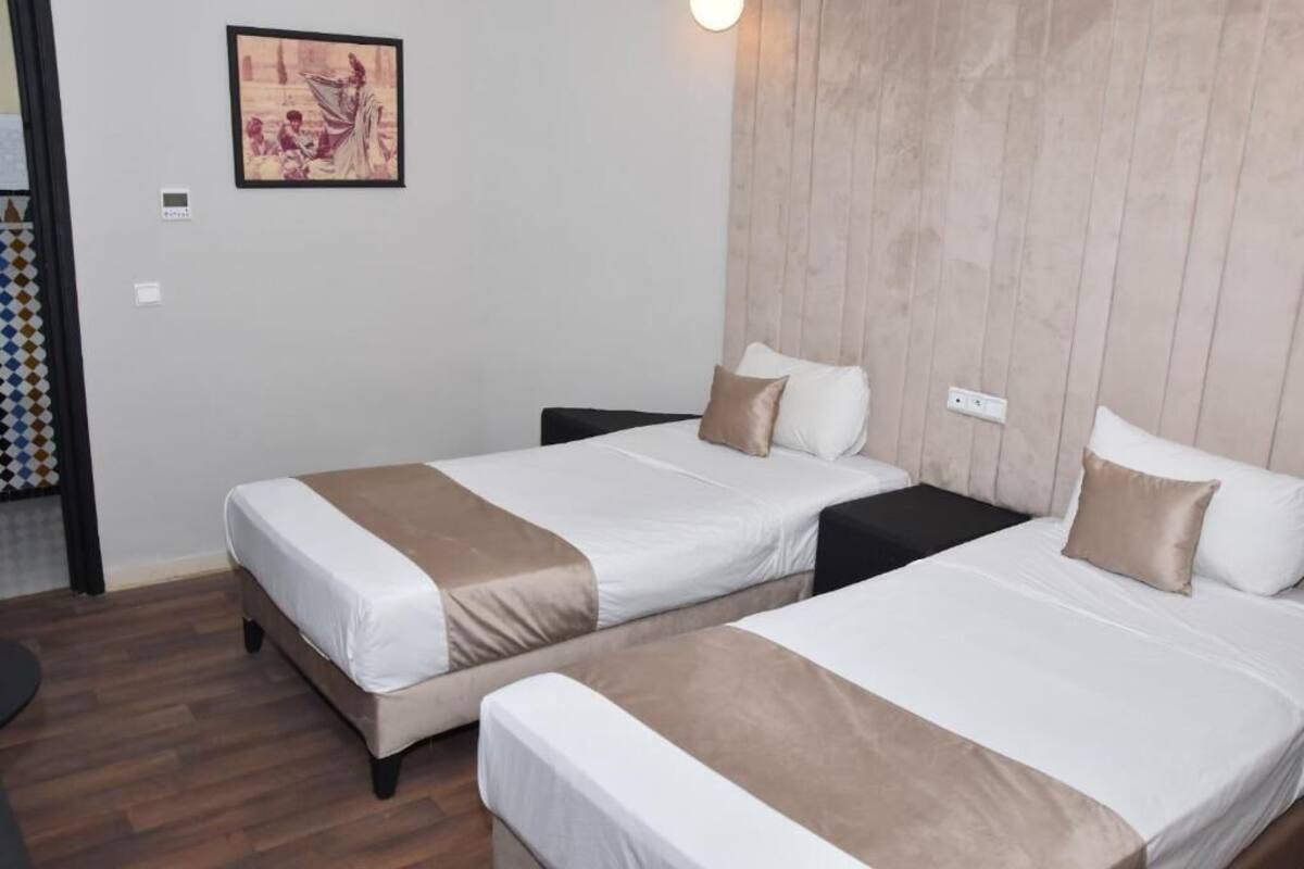 A hotel room with two beds, a wooden headboard, and a framed picture on the wall.