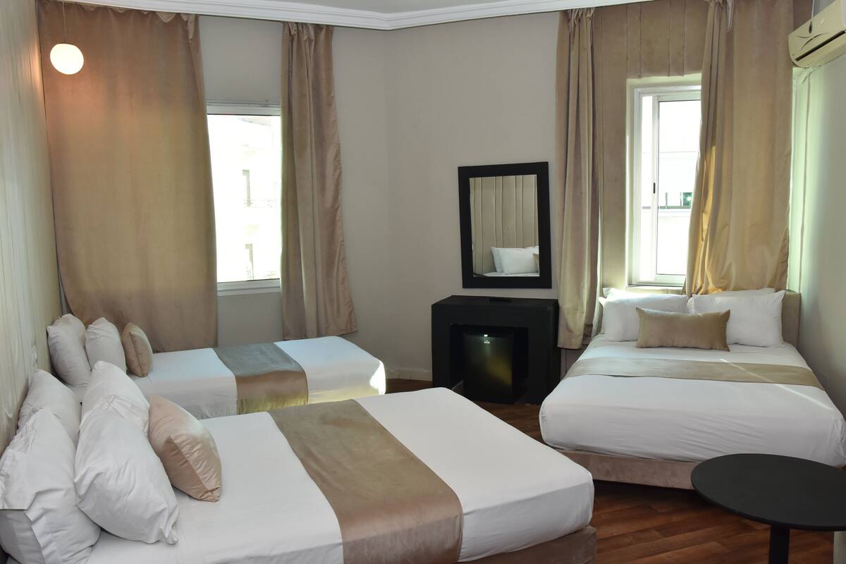 A hotel room with two beds, a small table, a TV, and a mirror.