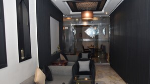 A modern living room with a grey sofa, black and white checkered chairs, a glass coffee table, and a chandelier. - Cadé Hotel (Casablanca)