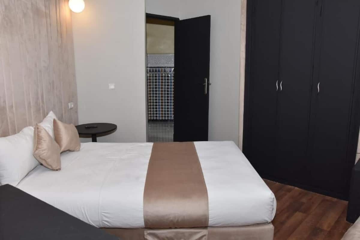 A hotel room with a bed, a small round table, and a wardrobe.