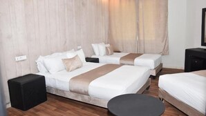 A hotel room with two beds, a small table, and a wall-mounted TV. - Cadé Hotel (Casablanca)