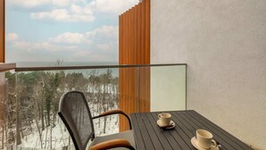 A balcony with a view of a snowy forest, a table with two cups, and a chair. - Studio with Sea View | Parking | By the Beach (Pobierowo)