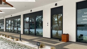 A modern building with large glass doors and a sign indicating a location. - Studio with Sea View | Parking | By the Beach (Pobierowo)