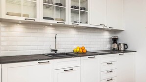A kitchen with white cabinets, a black countertop, and a coffee maker. - Studio with Sea View | Parking | By the Beach (Pobierowo)