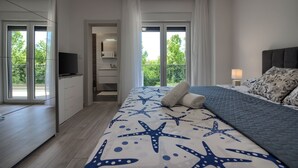 A modern bedroom with a large bed, a TV, and a balcony with a view of greenery. - Villa Ema with private pool by WiiBuk (Istria - Sisan) (Sisan)
