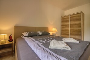 A neatly made bed with pillows, a bedside lamp, and a nightstand with a lamp. - Villa Irma (Istria - Rovinj) (Rovinj)