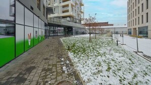 A modern building with a covered walkway, a snow-covered garden, and a clear sky. - Elegant Apartment | Air Conditioning | Balcony | Workspace. (Wroclaw)
