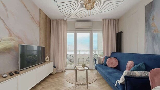 A modern living room with a TV, sofa, and a view of the outdoors. - Elegant Apartment | Air Conditioning | Balcony | Workspace. (Wroclaw)