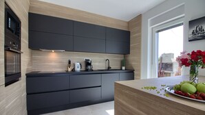 Una cucina moderna con mobili scuri, un piano di lavoro in legno e un'ampia finestra.