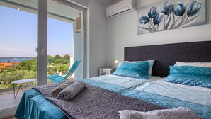 A bedroom with a large bed, a view of the sea, and a balcony with a chair. - Villa Horizont (Istria - Fažana) (Fažana)