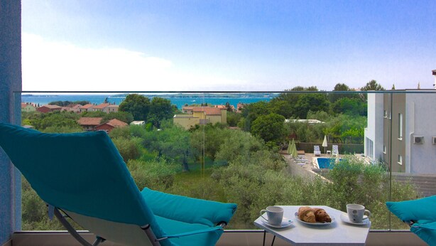 A balcony with a table set for breakfast, overlooking a coastal town and a clear blue sky. - Villa Horizont (Istria - Fažana) (Fažana)